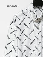 White long-sleeve button-up shirt with black Balenciaga logo pattern, angled close-up