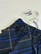 Navy plaid shorts waistband with drawstring and metal eyelets, with attached tags
