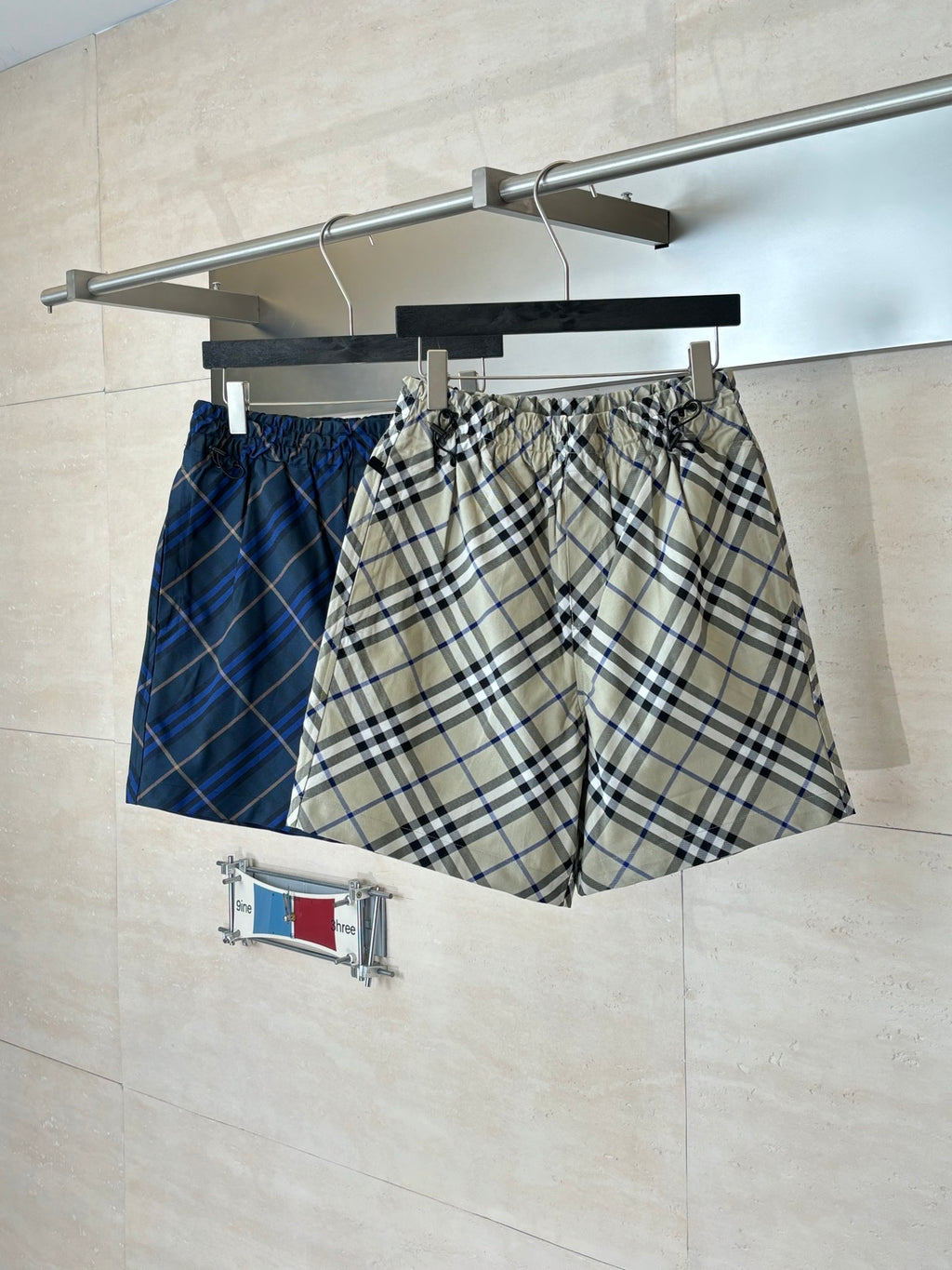 Plaid pants on hanger, beige blue and black check pattern, elastic waistband and drawstring