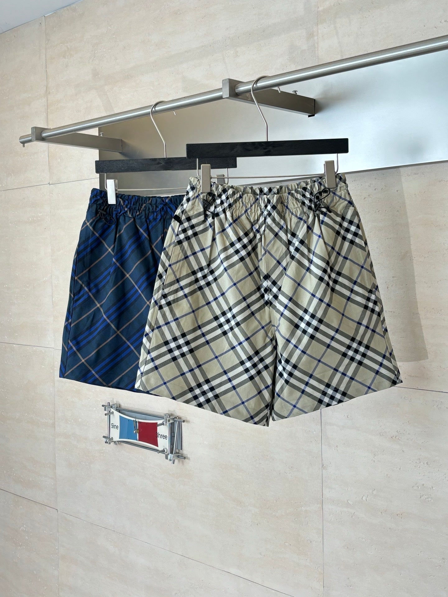 Plaid pants on hanger, beige blue and black check pattern, elastic waistband and drawstring
