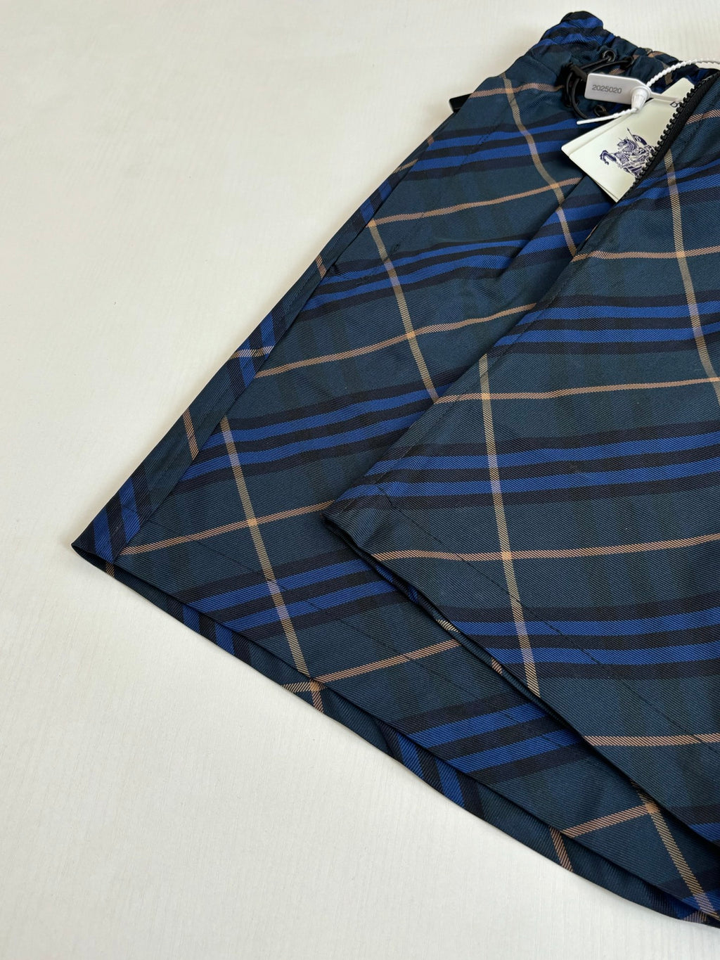 Navy plaid shorts laid flat with front button closure, blue and tan check pattern