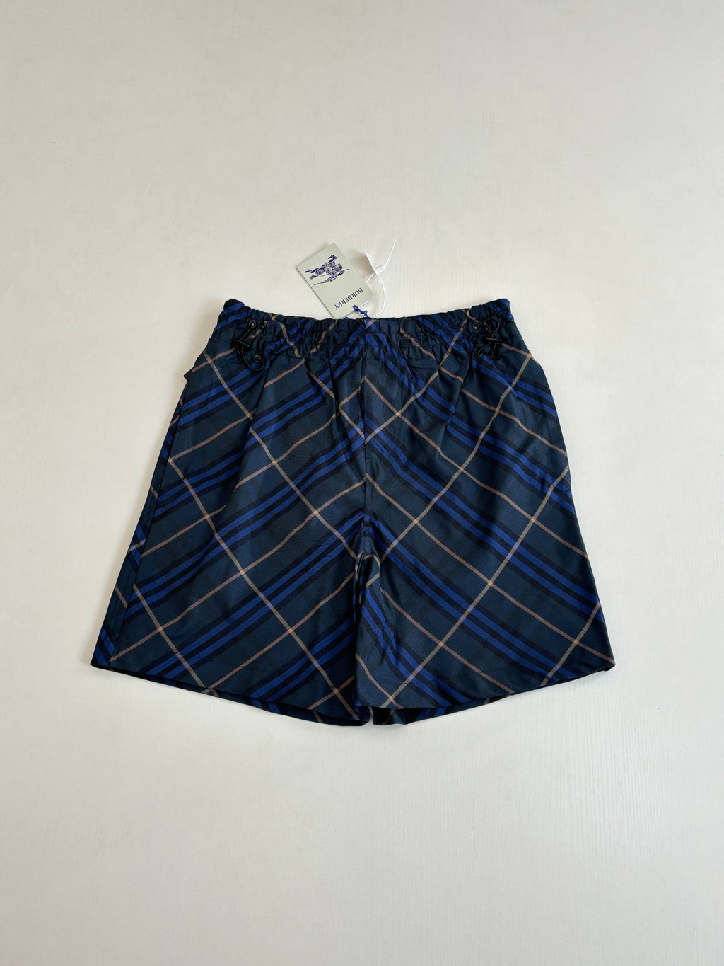 Navy plaid shorts with elastic waistband and front pleats, blue and tan check pattern
