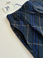 Navy plaid shorts fabric close-up with elastic waistband and drawcord ties