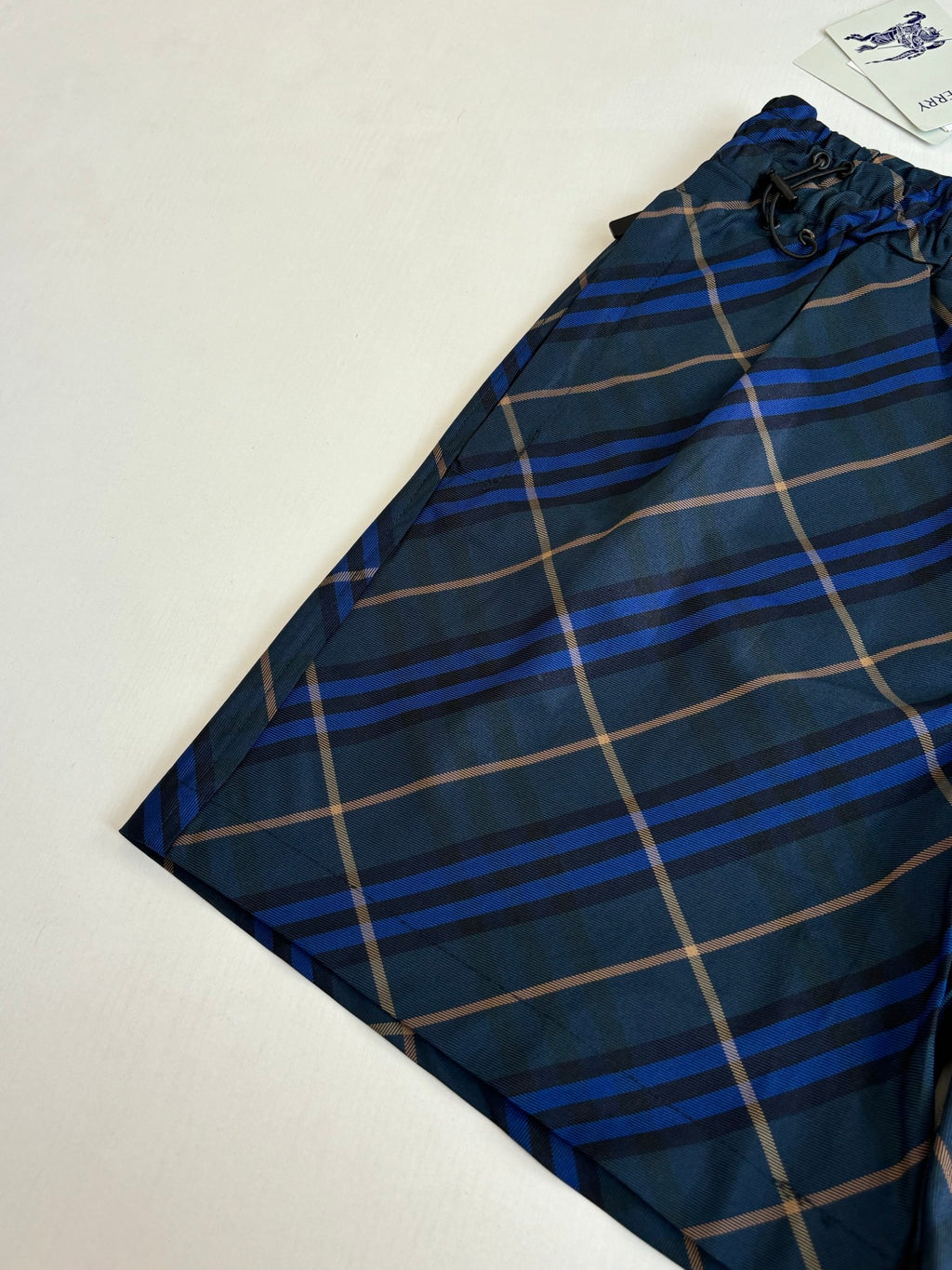 Navy plaid shorts side view with elastic waistband and drawstring details
