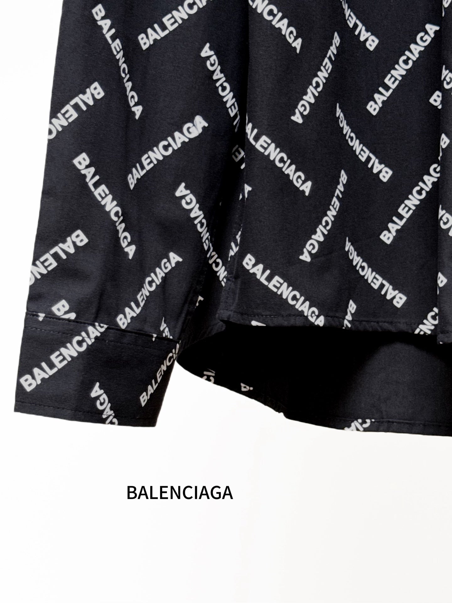 Black long-sleeve shirt with Balenciaga logo pattern, cropped view of sleeves and hem