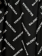 Black fabric close-up with Balenciaga logo print and visible button-front placket