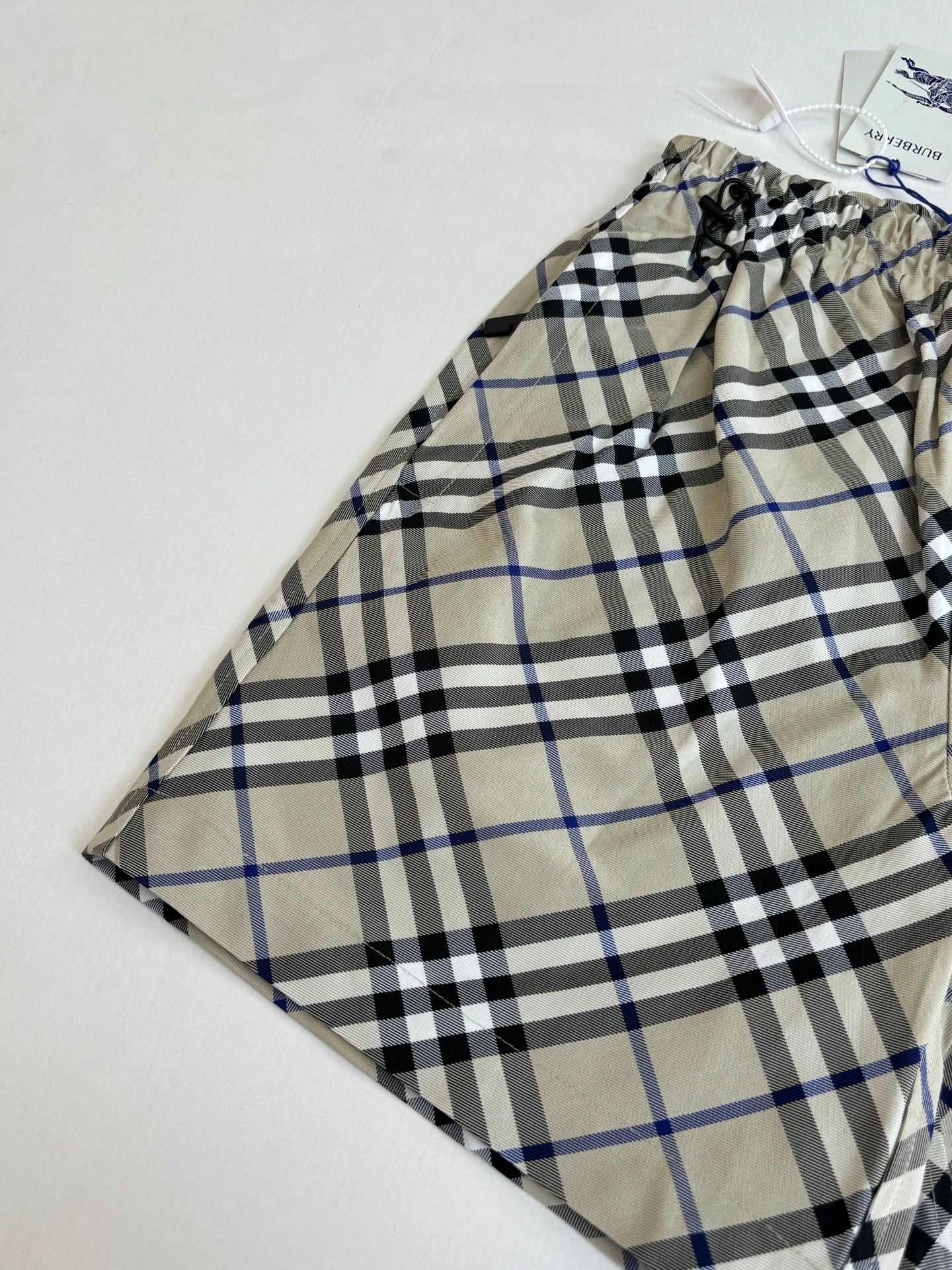 Plaid pants with drawstring waist, beige blue and black checks, laid flat with tag
