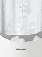 White long-sleeve button-up shirt hem with buttons and gathered fabric at waist