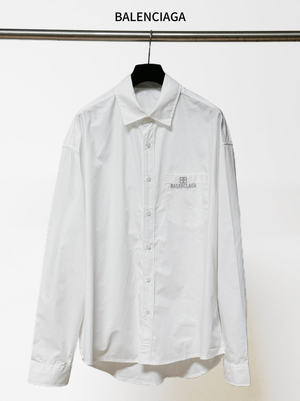 White long-sleeve button-up shirt with pointed collar and chest logo patch