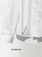 White long-sleeve button-up shirt showing folded hem and partial button placket