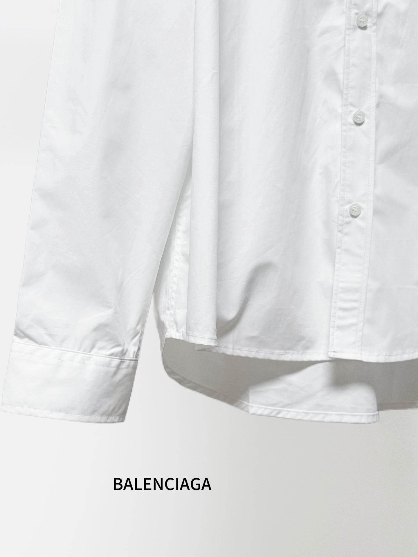 White long-sleeve button-up shirt showing folded hem and partial button placket