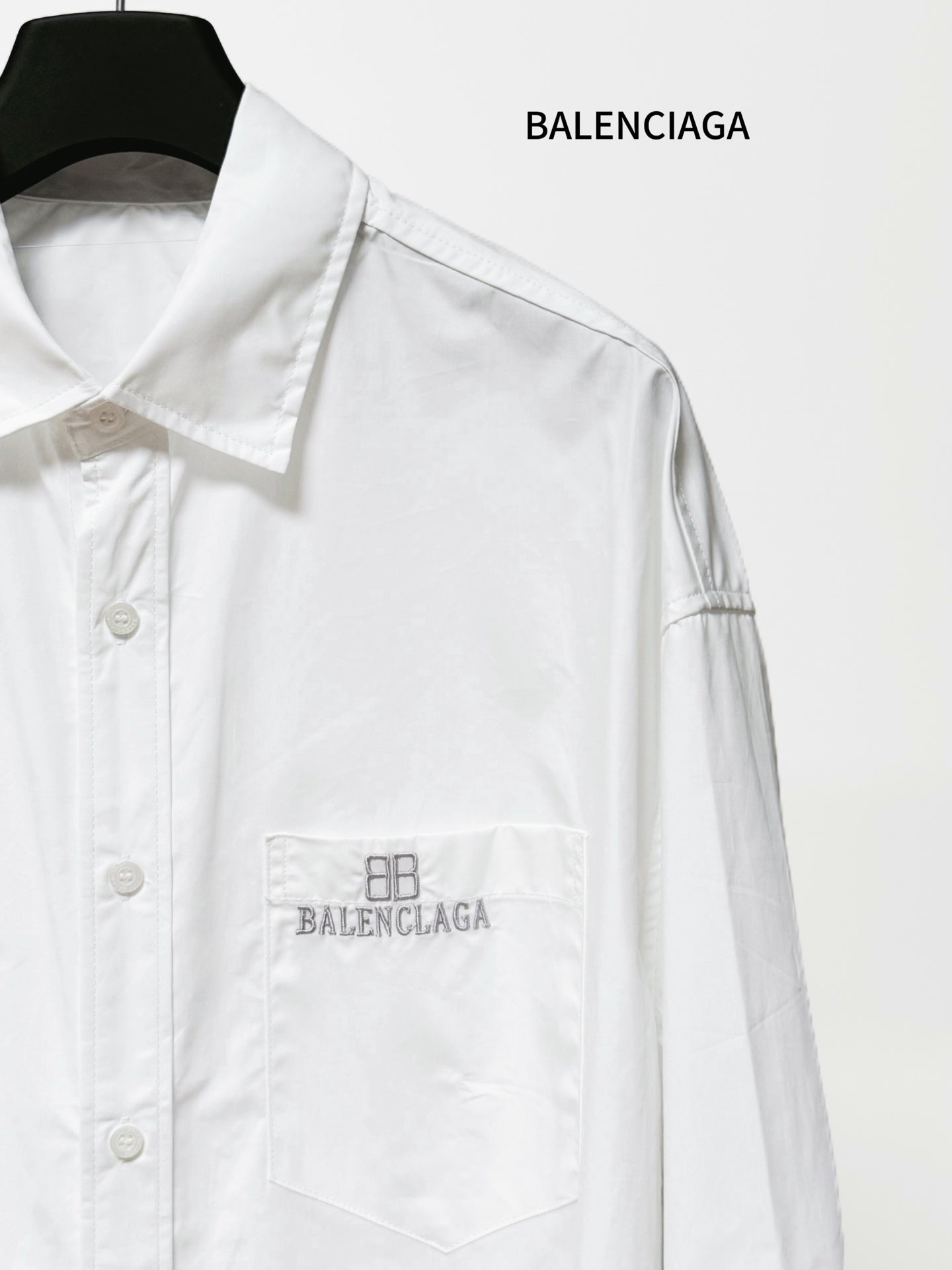 White long-sleeve button-up shirt close-up of chest pocket with Balenciaga embroidery