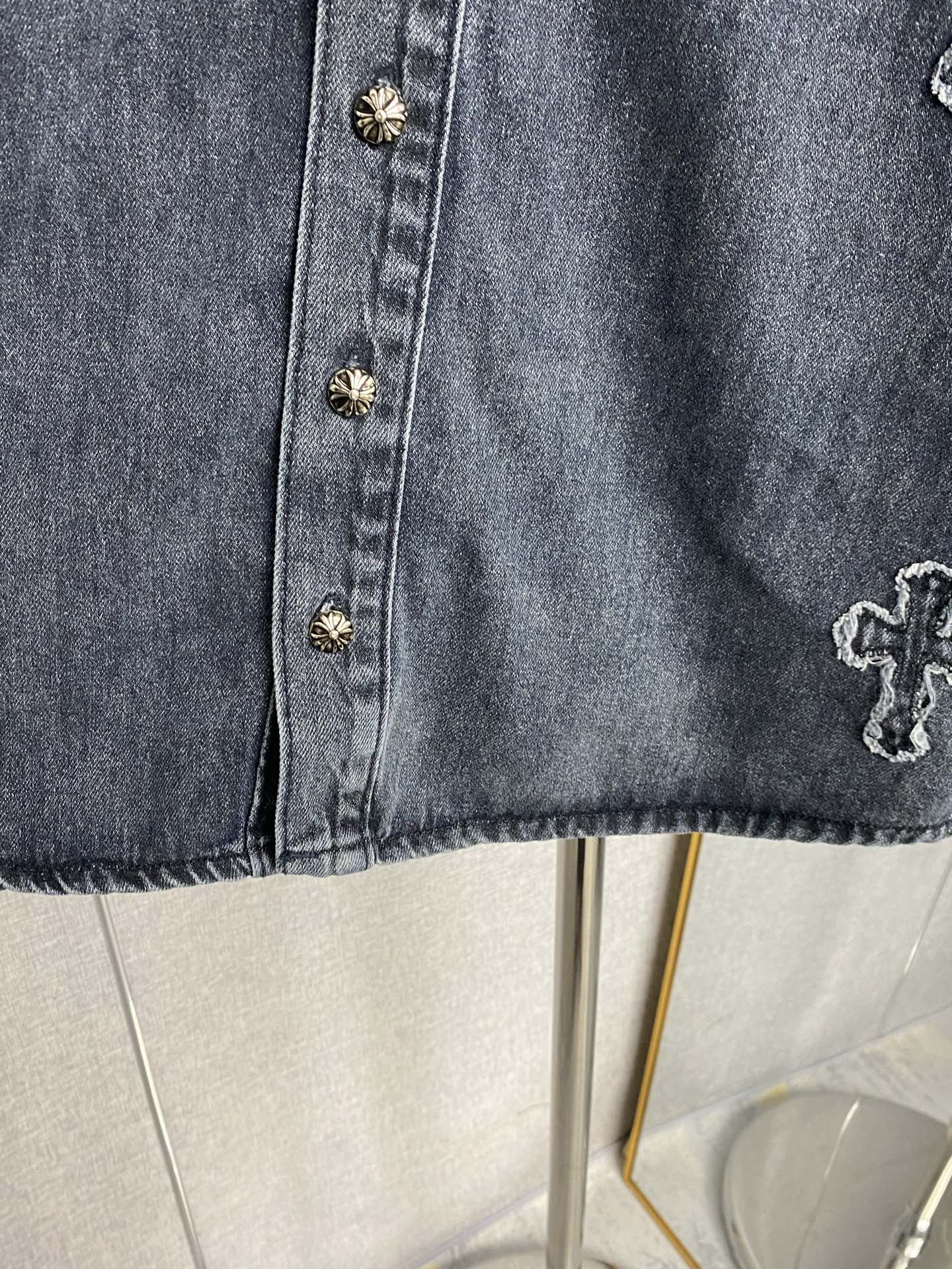 Denim jacket front with gold buttons and embroidered cross motif