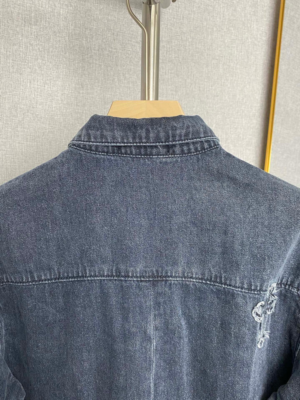 Back of dark blue denim jacket with contrast stitching and small embroidered cross