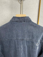 Back of dark blue denim jacket with contrast stitching and small embroidered cross