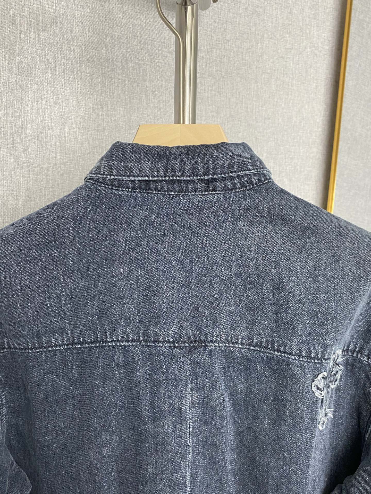 Back of dark blue denim jacket with contrast stitching and small embroidered cross