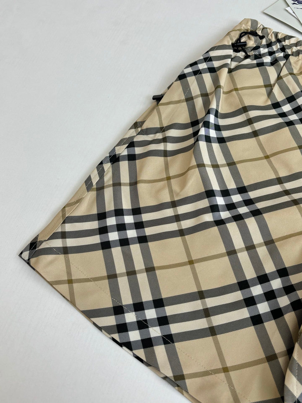 Burberry plaid shorts fabric close-up with beige base and black check pattern.