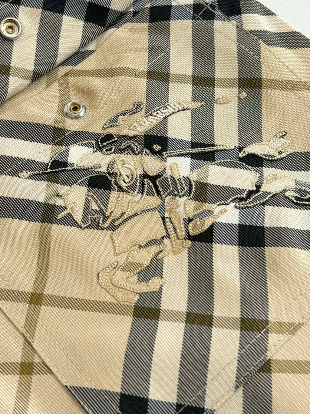 Burberry plaid shorts embroidery patch detail on beige and black check fabric.