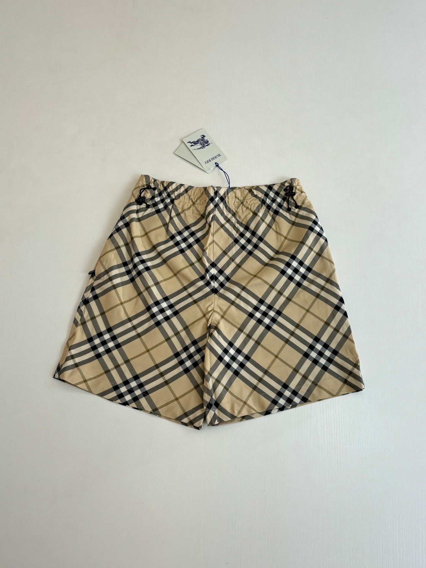 Burberry plaid shorts laid flat, elastic waistband with drawstring and front seam.