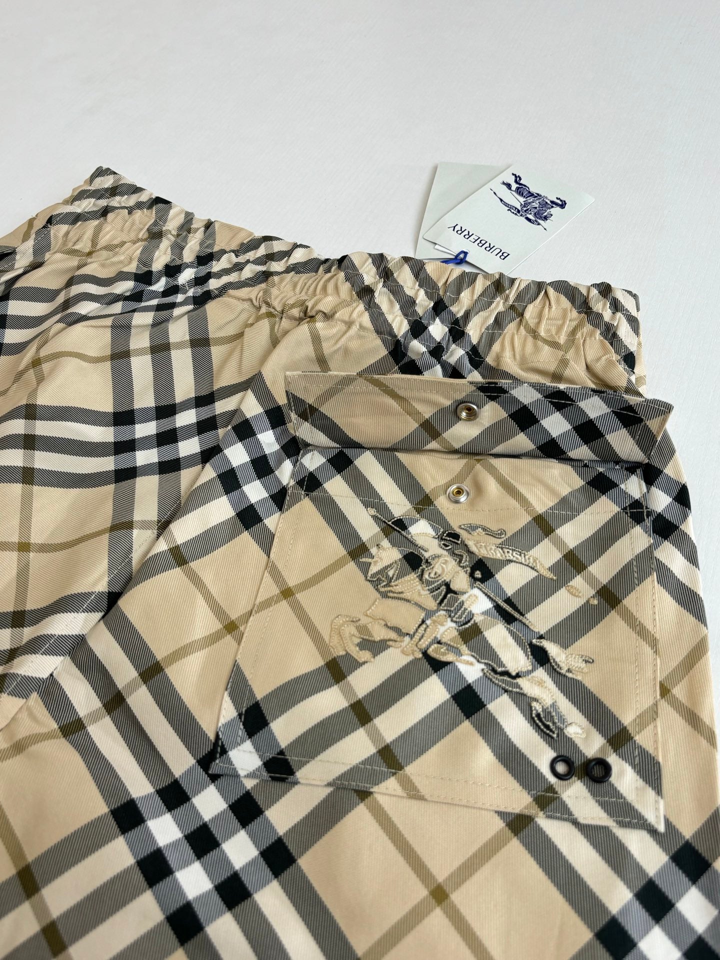 Burberry plaid shorts close-up showing elastic waist and front buttoned placket.