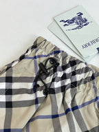 Plaid waistband close-up with black drawstring ties and brand label, beige blue and black checks