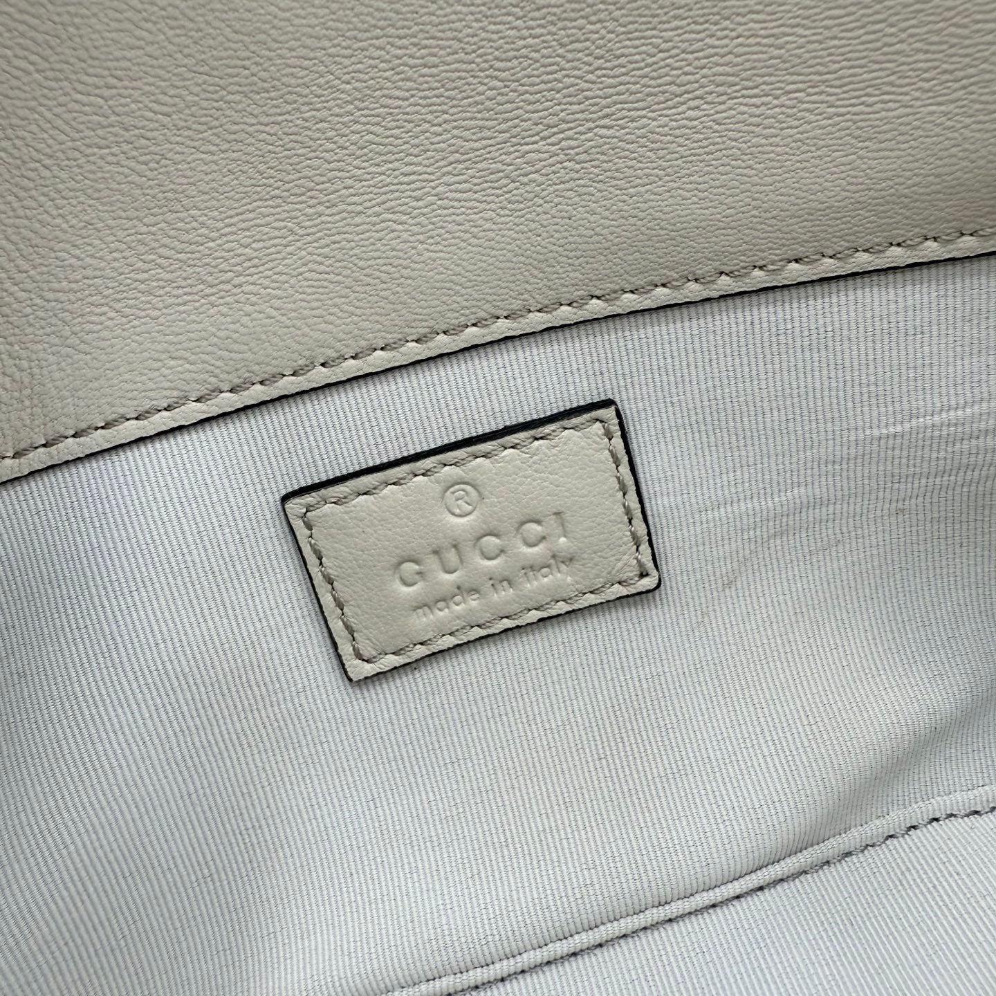 Small quilted bag close-up of stitched fabric logo patch on light lining