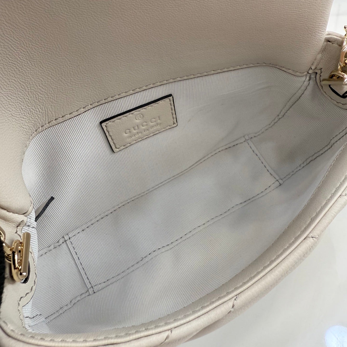 Small quilted bag interior lining with fabric logo tag and side seam stitching