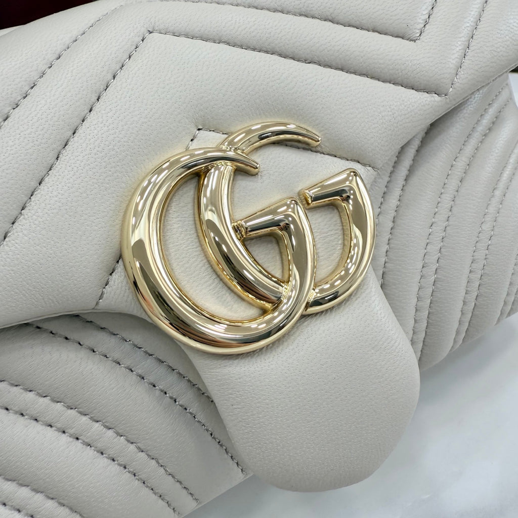 Close-up of off-white quilted leather bag with gold-tone GG logo hardware