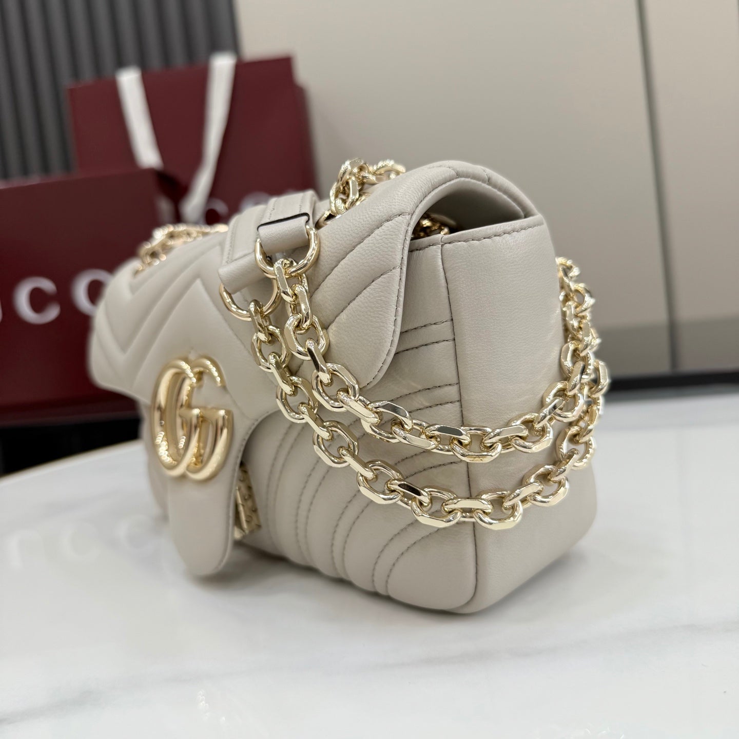 Off-white quilted leather shoulder bag with gold-tone chain and GG logo charm