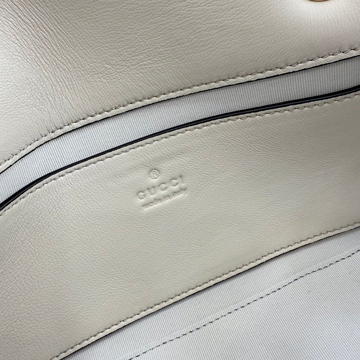 Gucci logo embossing on off-white leather lining inside the bag