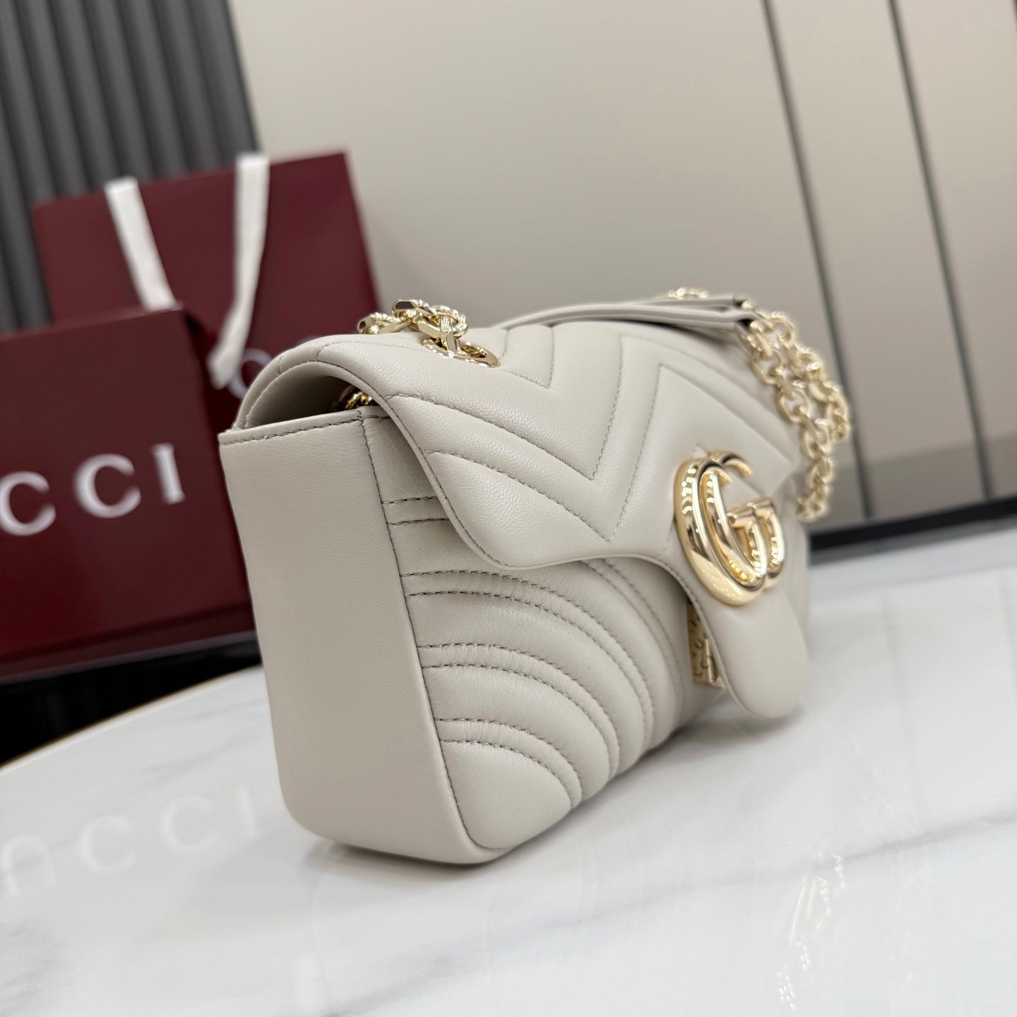 Off-white quilted leather shoulder bag with gold-tone chain, side flap, and GG emblem