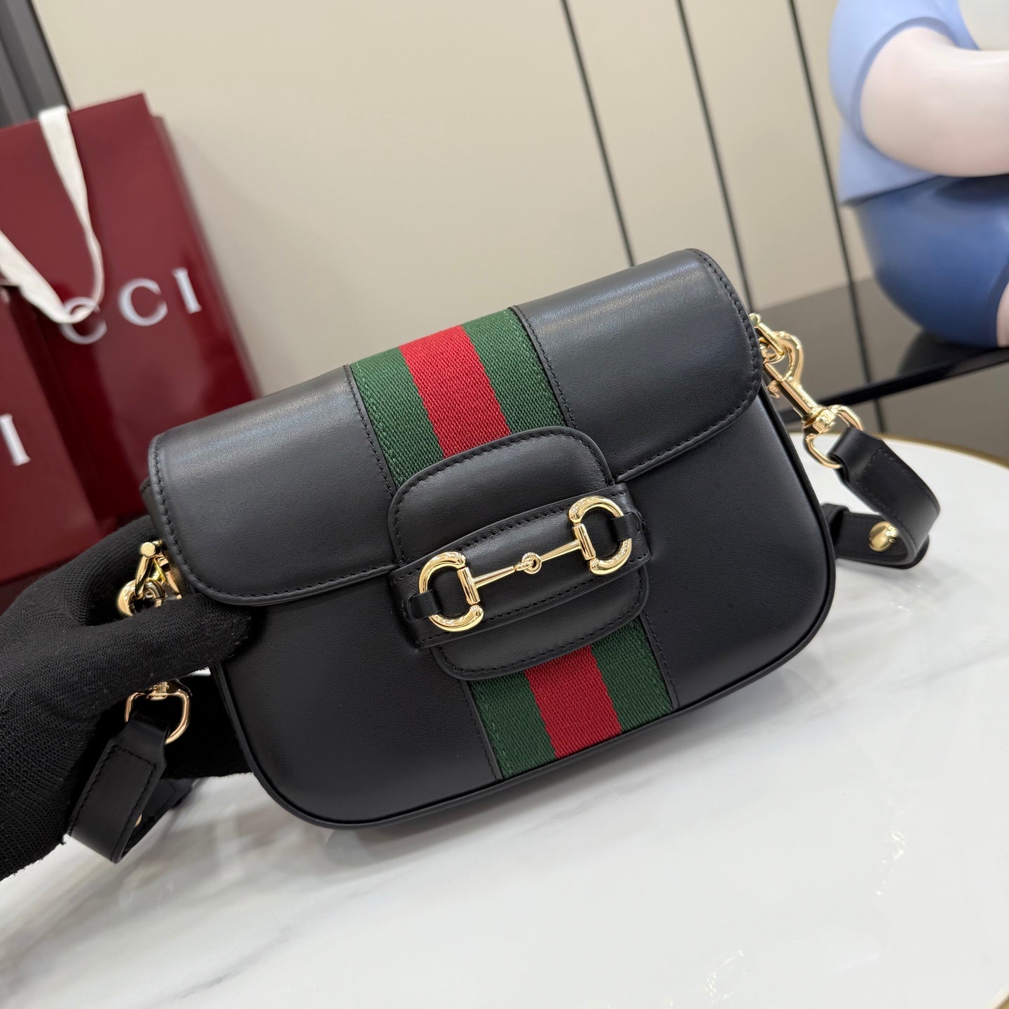 Gucci crossbody bag with black leather flap and green-red stripe, gold-toned clasp, adjustable strap