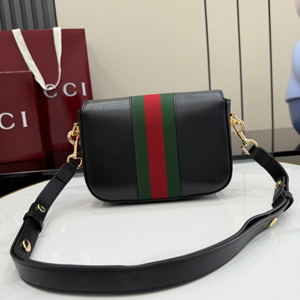 Gucci crossbody bag front view with black leather, green and red web stripe, long strap