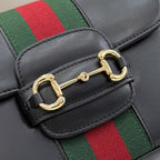 Gucci crossbody clasp detail on black leather flap with gold buckle hardware and green-red web stripe