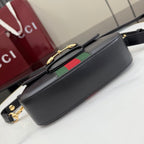 Gucci crossbody bag angled view with black leather and gold zipper hardware, green-red stripe