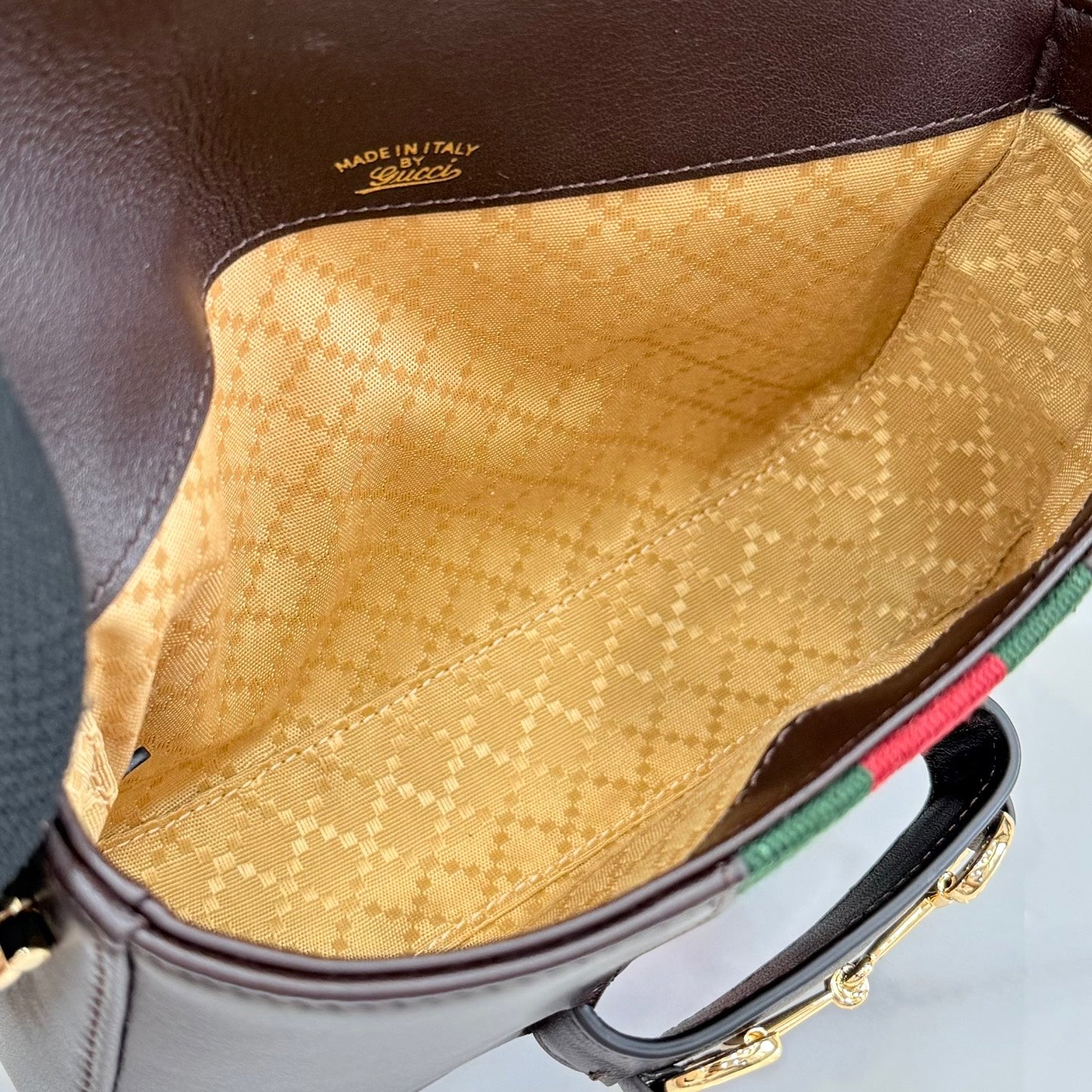 Interior lining close-up in tan with embossed pattern inside dark brown flap bag