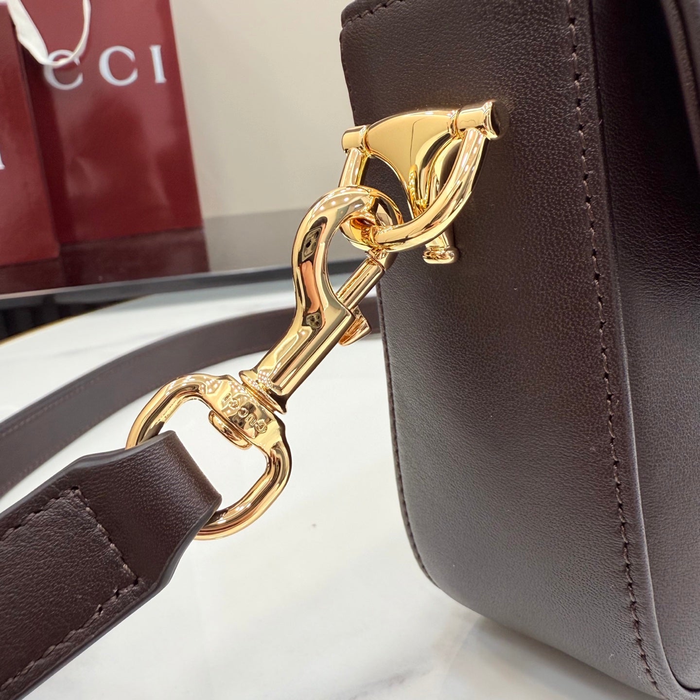 Gold tone clasp and chain hardware on dark brown leather bag strap
