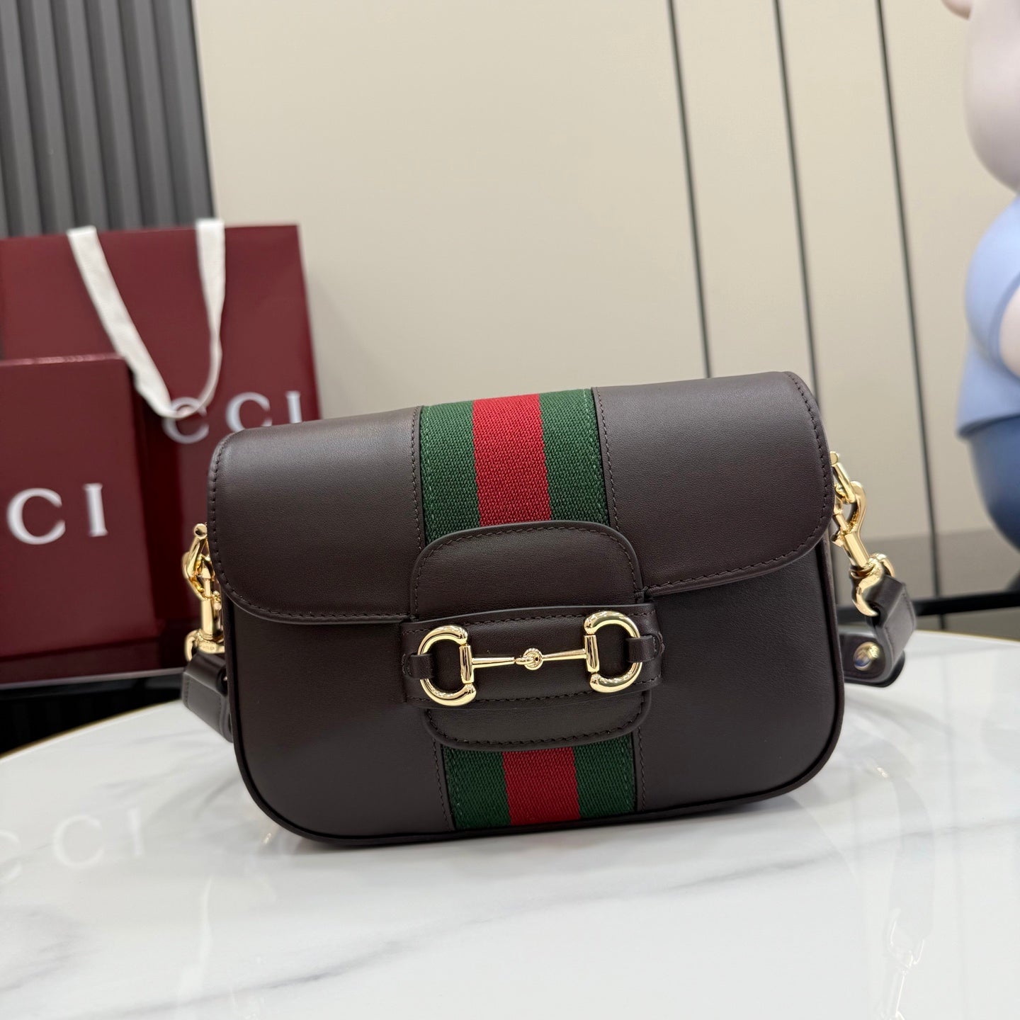 Dark brown leather crossbody bag with green and red striped band and flap closure