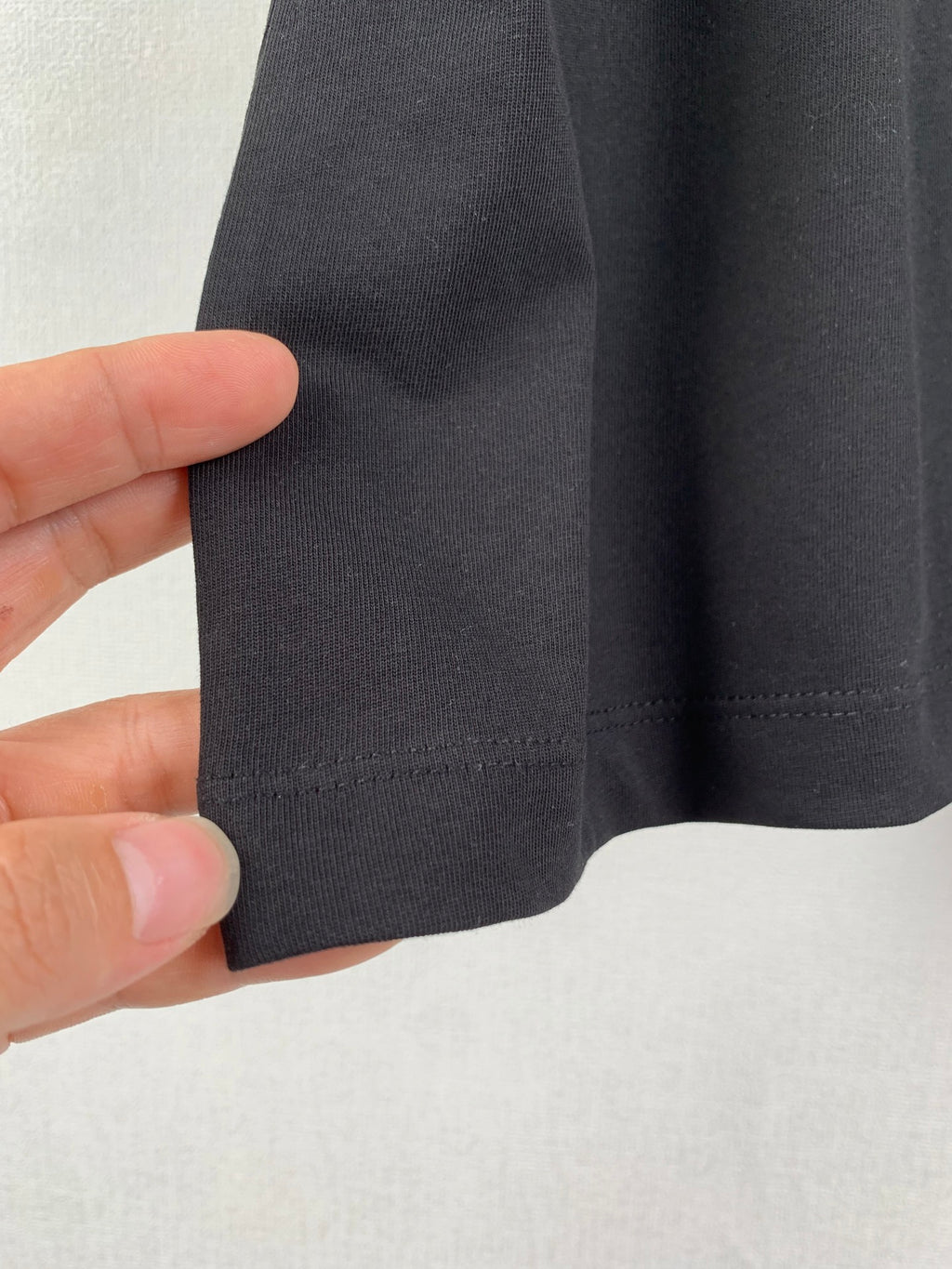 Black T-shirt fabric texture and hem stitching close-up