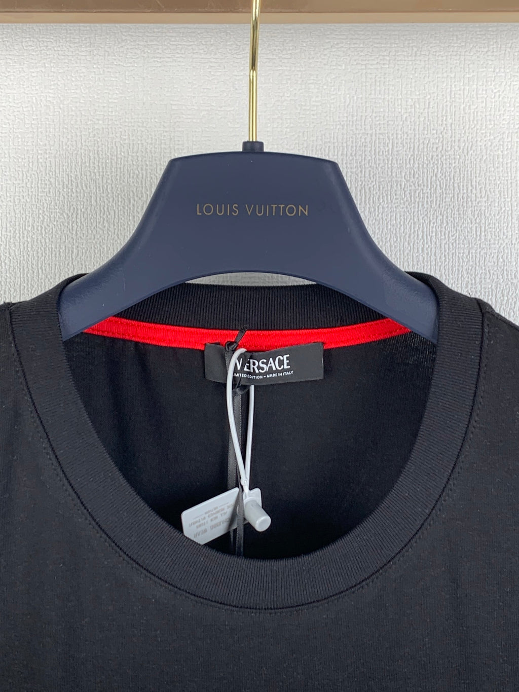 Black T-shirt neckline with red inner collar trim and Versace neck label