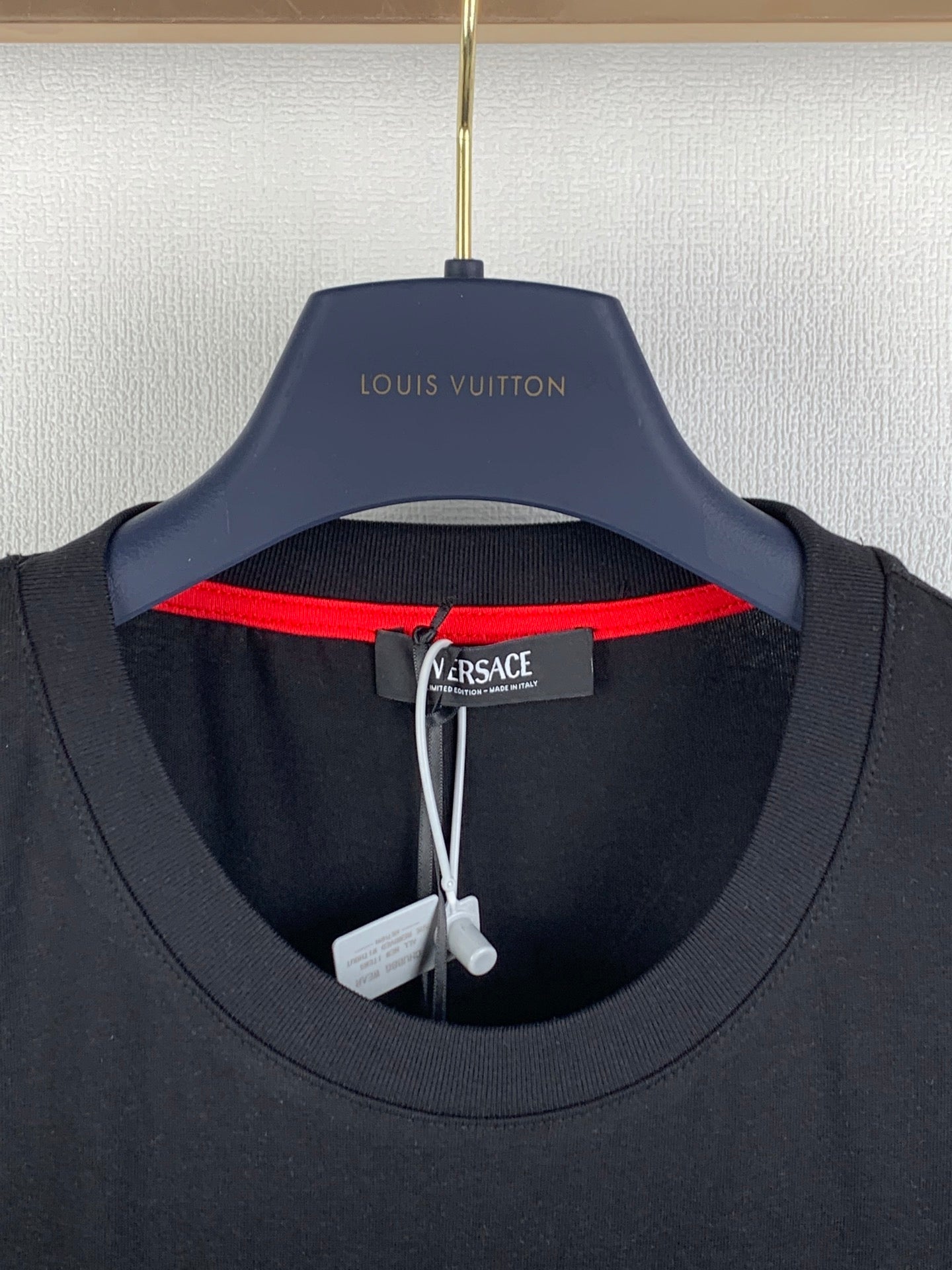 Black T-shirt neckline with red inner collar trim and Versace neck label