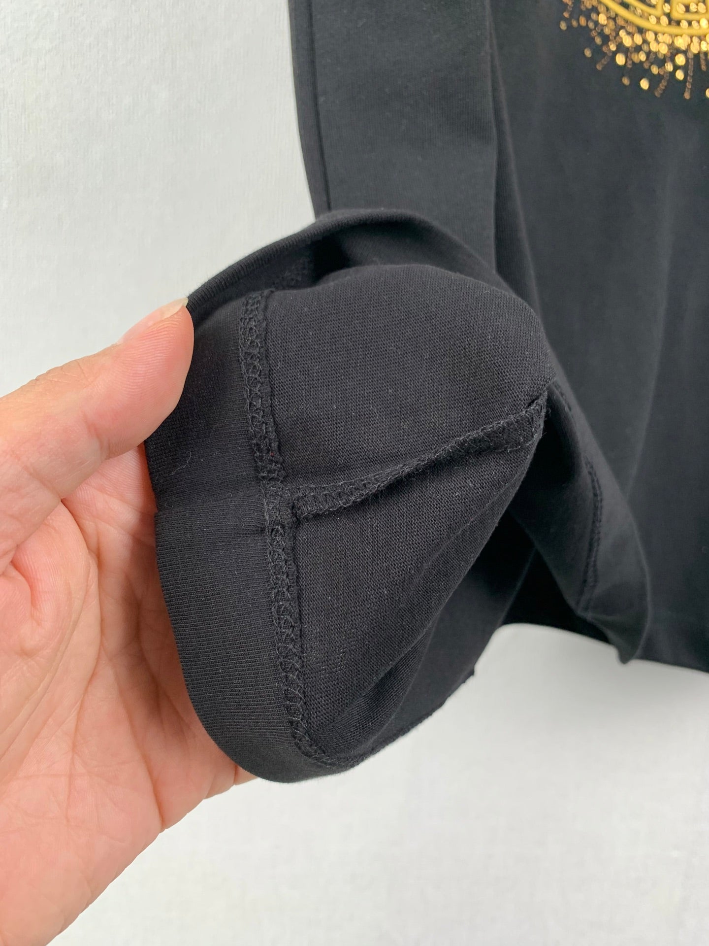 Black T-shirt sleeve cuff with seam stitching close-up