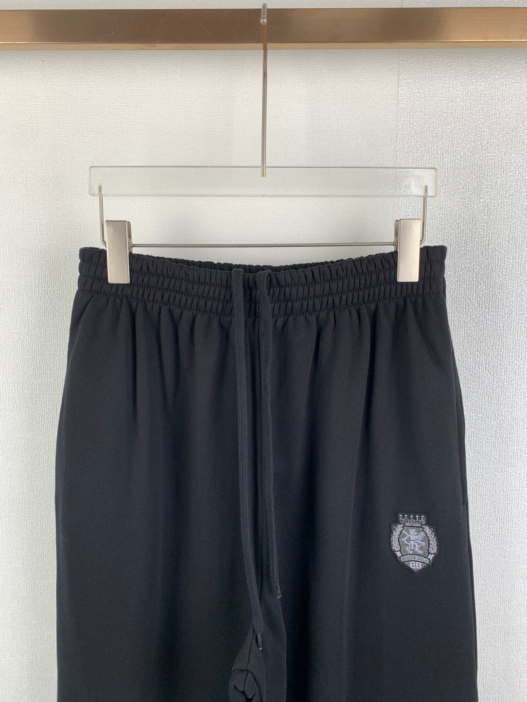 Balenciaga pants with elastic waistband and dark crest logo patch on thigh