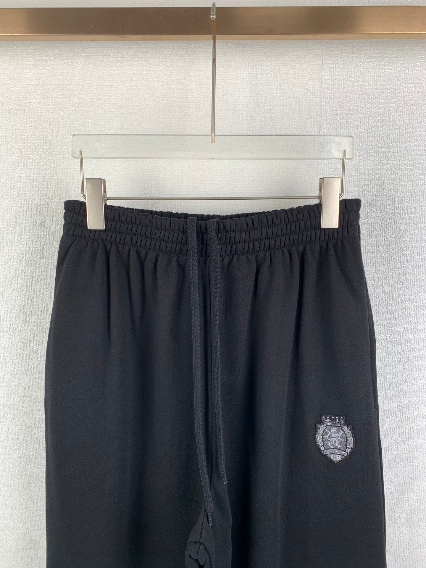 Balenciaga pants with elastic waistband and dark crest logo patch on thigh