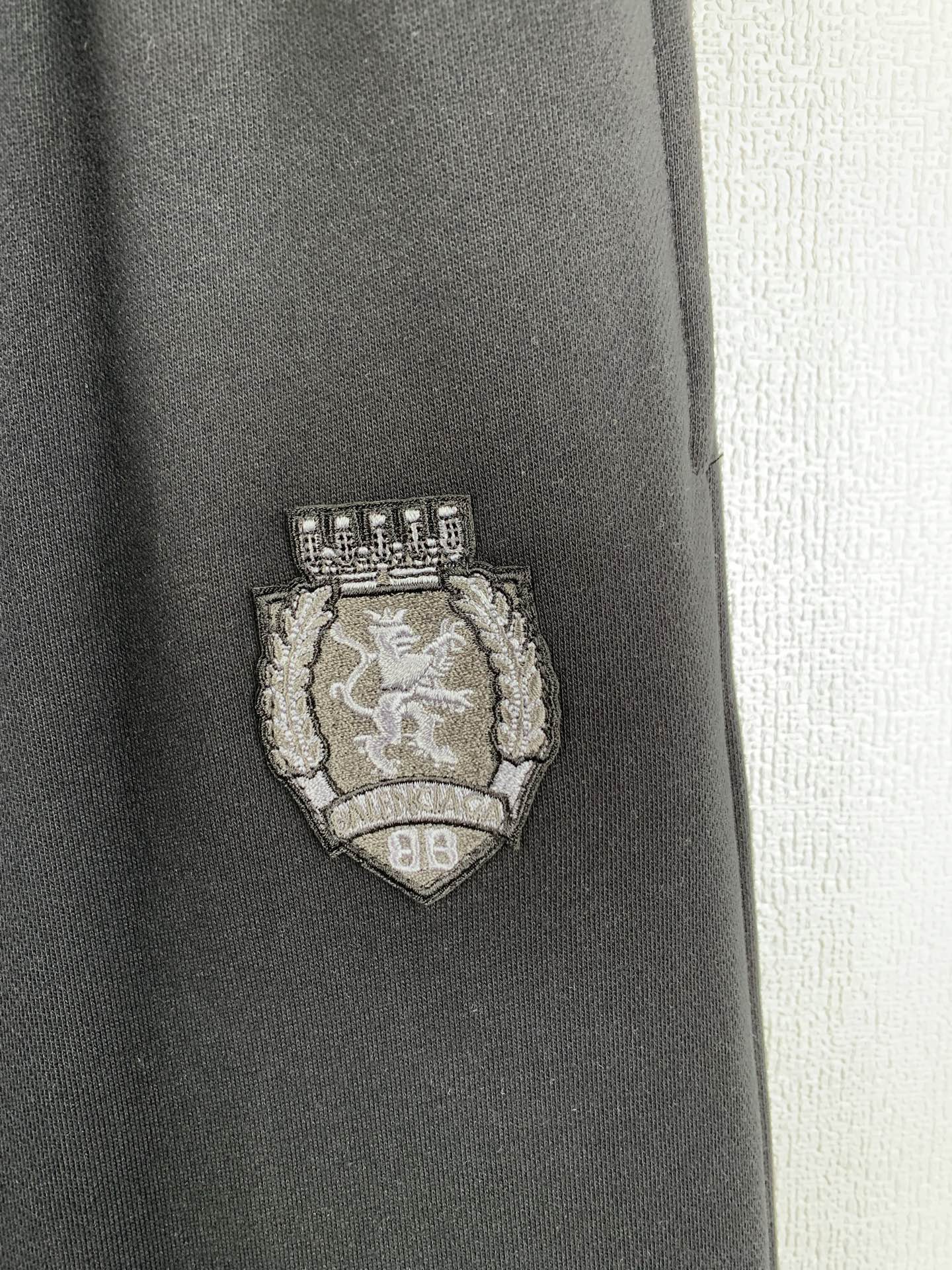 Balenciaga pants with embroidered crest logo patch on dark fabric