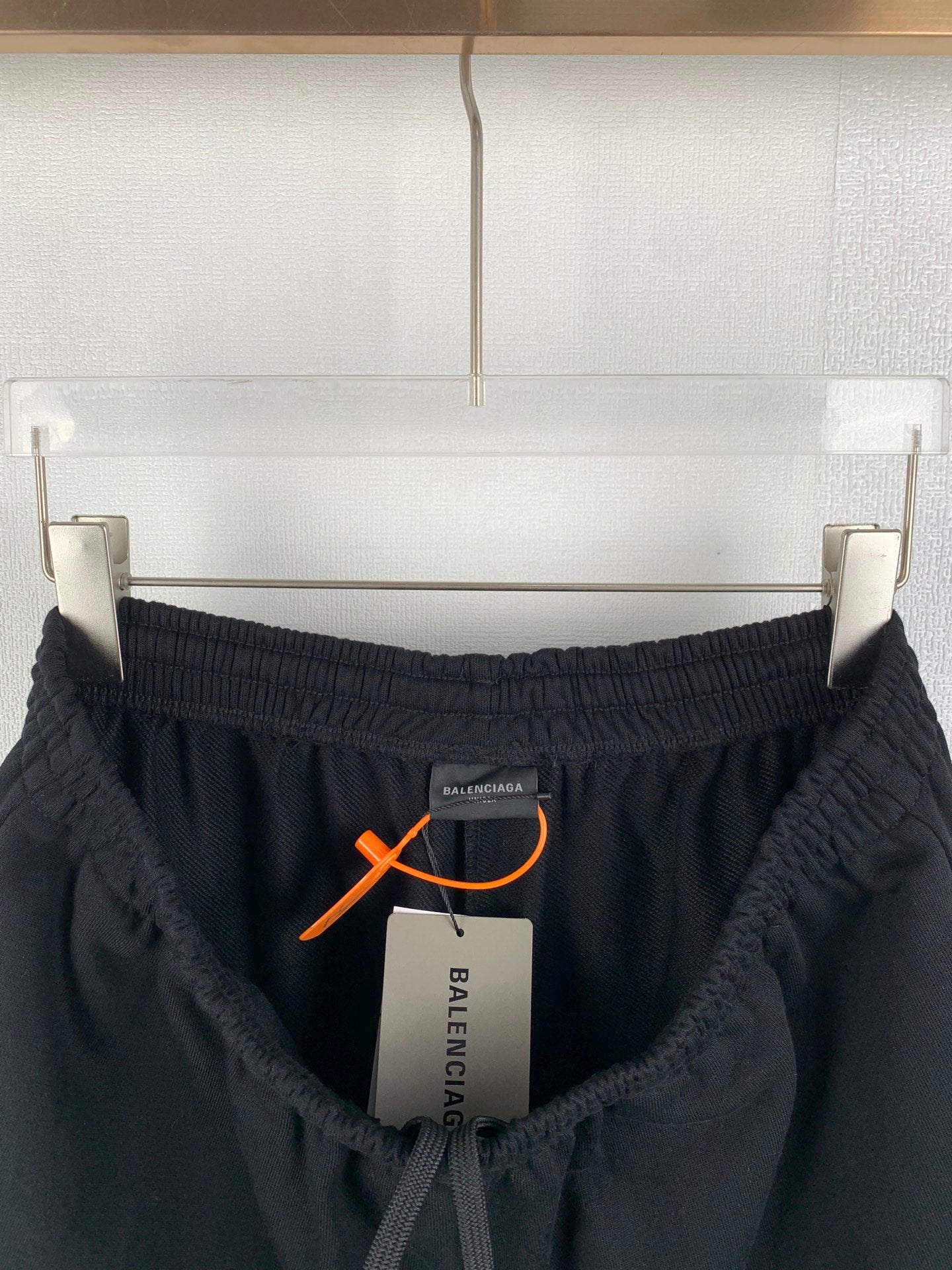 Black Balenciaga pants with elastic waistband and orange drawstring toggle