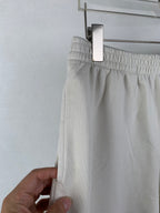 White shorts with elastic waistband, held up at the side seam by a hand