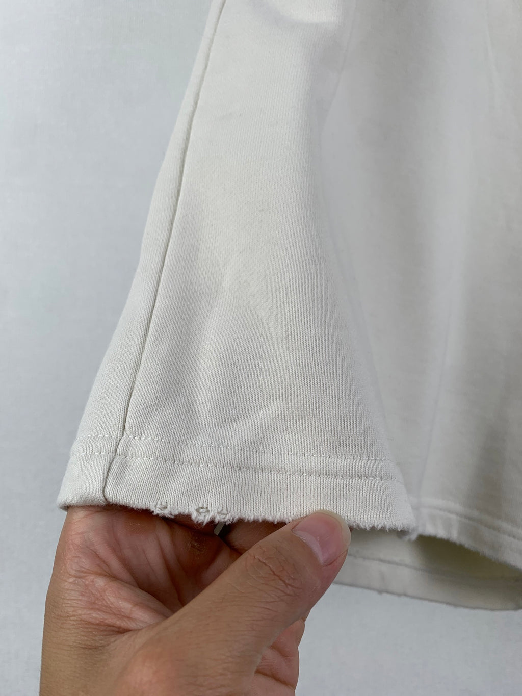 White shorts hem with visible stitching and textured fabric