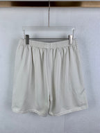 White elastic-waist shorts with pleated front and relaxed drape