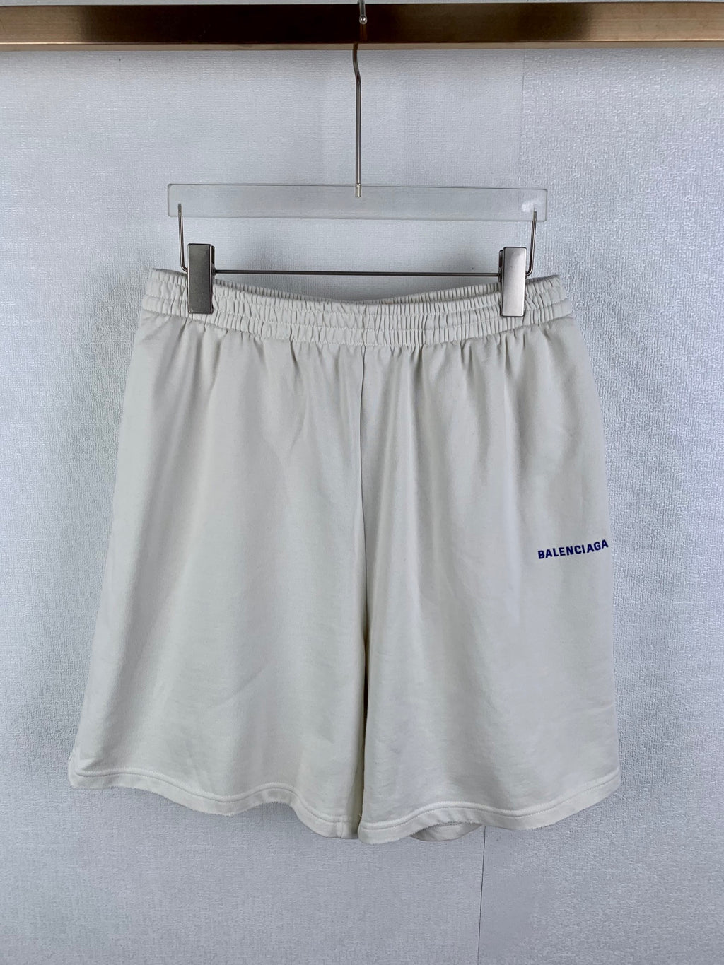 White elastic-waist shorts with pleated front and blue BALENCIAGA logo on side